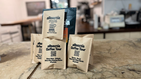 Roastia coffee packages on a stone surface with a blurred cafe background