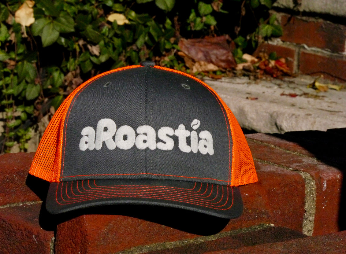 Front facing view of the aRoastia hat, showing the stitching of the letters and the brown and orange color scheme of the hat. Stitching is in white.