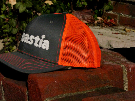 Side view of the hat showing the profile of the charcoal front section and the orange mesh back section.