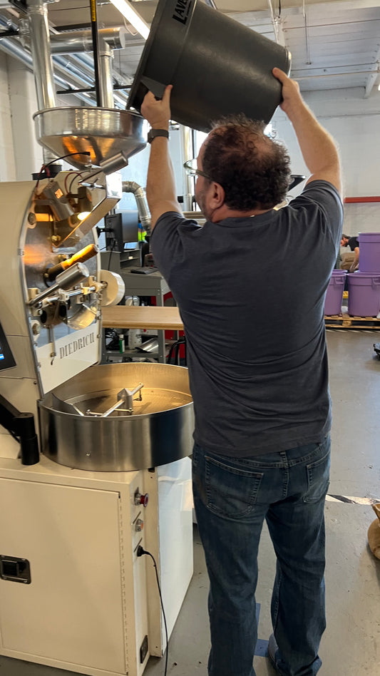 This photo shows Andy Hollander, owner of aRoastia, pouring beans into a Diedrich coffee roaster to begin the roasting process.