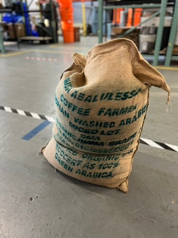 A photo of the bag of unroasted coffee beans sealed up in a burlap sack at the roastery.